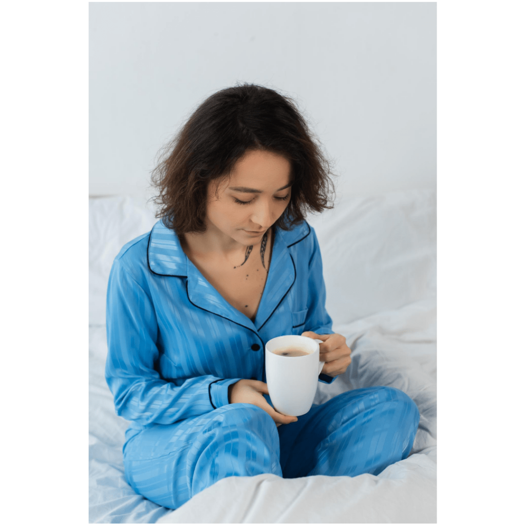 Mujer sentada en la cama tomando café en pijama