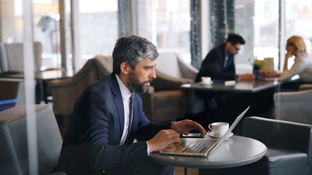 persona escribiendo un email en un laptop. la persona va vestida con un traje, dando imagen de profesionalidad