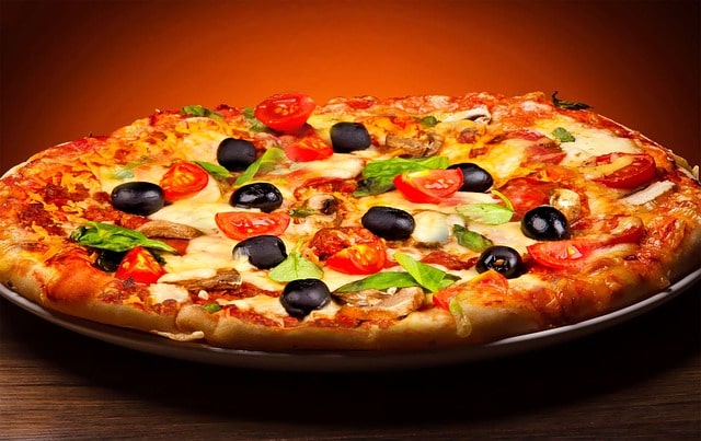 foto de una pizza vegetariana con tomate natural, aceitunas negras y más.